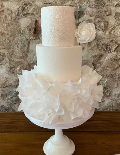 White wedding cake with ruffles and sugar flower at Schivas Steading